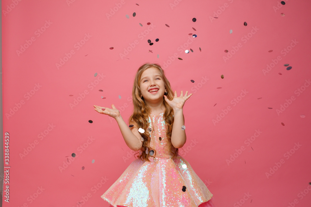 happy Little girl catches confetti on pink background, holiday concept happy Little girl catches confetti on pink background, holiday concept