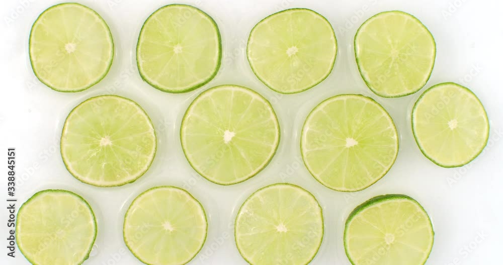 On a white background, sliced pieces of lime are sprinkled with water. Juicy fresh lime in slow motion. Lots of lime slices On a white background, sliced pieces of lime are sprinkled with water. Juicy fresh lime in slow motion. Lots of lime slices