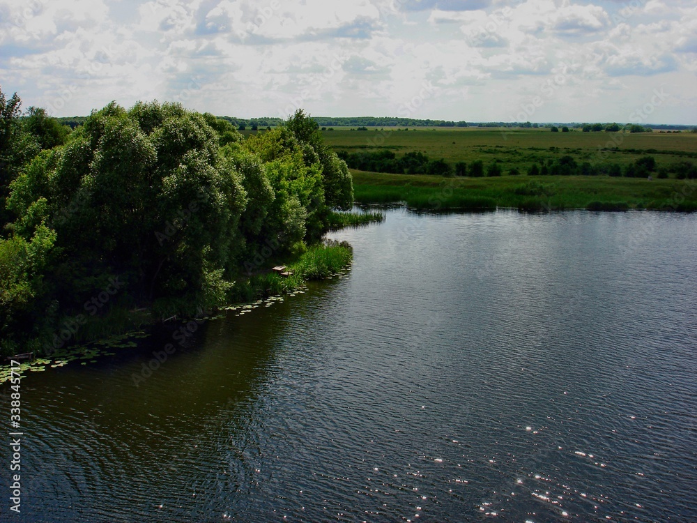 A beautiful river on a summer day in the Kursk region flows through green meadows.