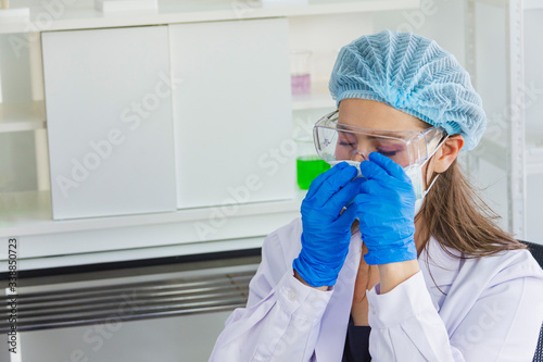 female scientist wearing safety glasses and a dark blue glove wearing hairnet,sitting in the laboratory protect coronavirus