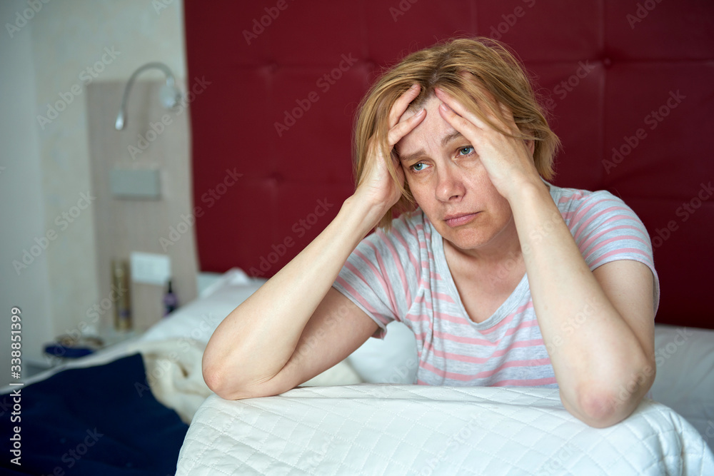 Woman with headache. A middle-aged woman is sitting on the bed, holding her head. Woman with headache. A middle-aged woman is sitting on the bed, holding her head.