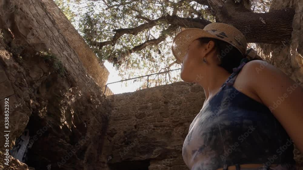 A shot from below of a girl in a purple dress looking towards the sky while sunbeams are passing through her sun hat. A sunny summer day exploring the catacombs in Cyrpus. A shot from below of a girl in a purple dress looking towards the sky while sunbeams are passing through her sun hat. A sunny summer day exploring the catacombs in Cyrpus.