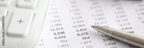Silver pen report with numbers next to calculator
