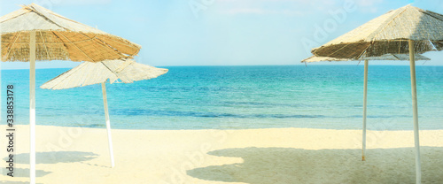 Beach umbrellas and clean sand against the backdrop of the azure coast of the sea. Vacation and Tourism concept.