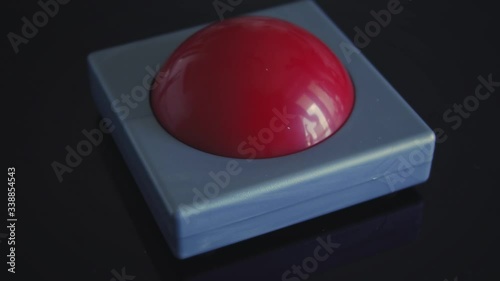 Hand pushing a small red buzzer. Button is triggered by a female hand. photo