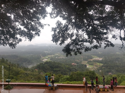 July 6, 2019- Karnataka, India: A landscape view of Raja's Seat park filled with fog in Coorg, Karnataka, India. People spectating the view.