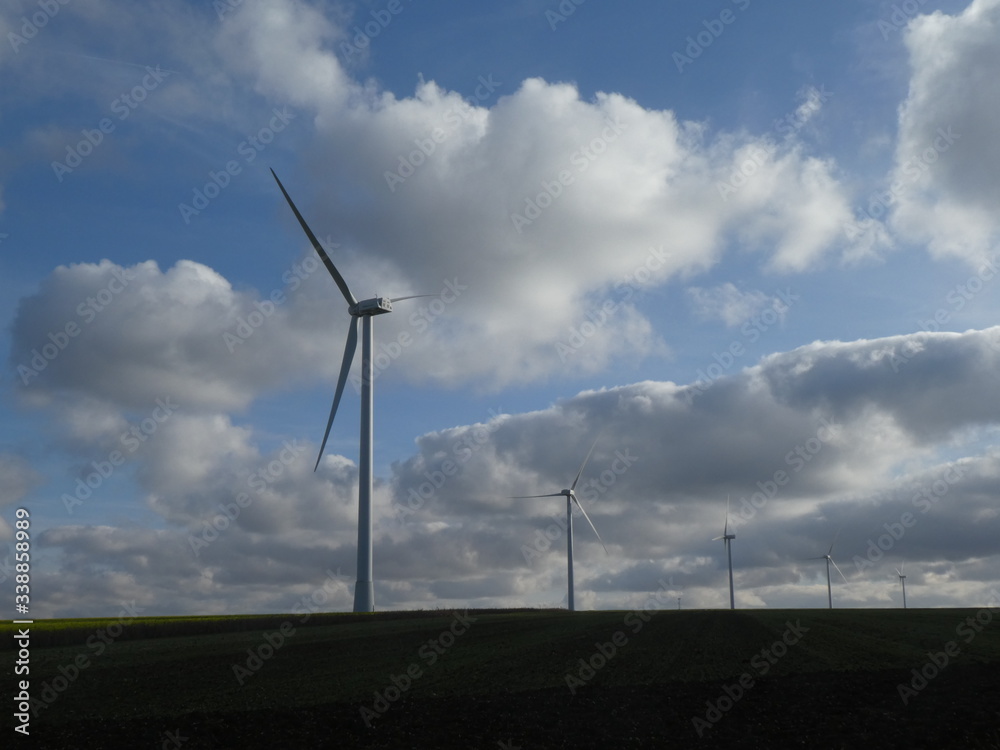 Row of five wind turbines surrounded by cottony clouds Row of five wind turbines surrounded by cottony clouds