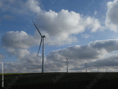 Row of five wind turbines surrounded by cottony clouds
