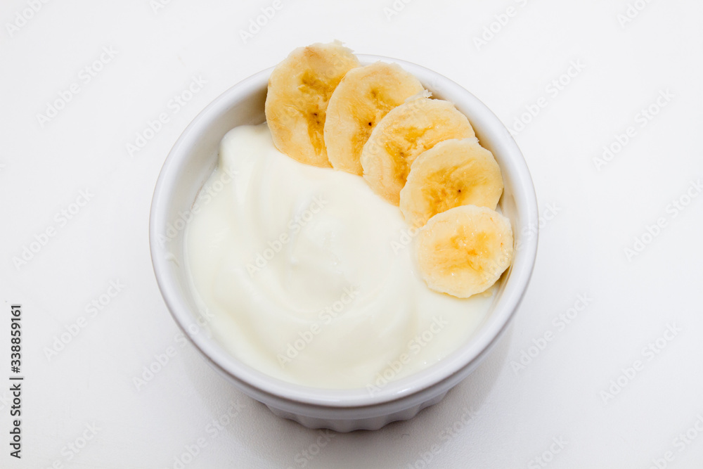Healthy breakfast: yogurt with and banana in a white bowl on the white table Healthy breakfast: yogurt with and banana in a white bowl on the white table