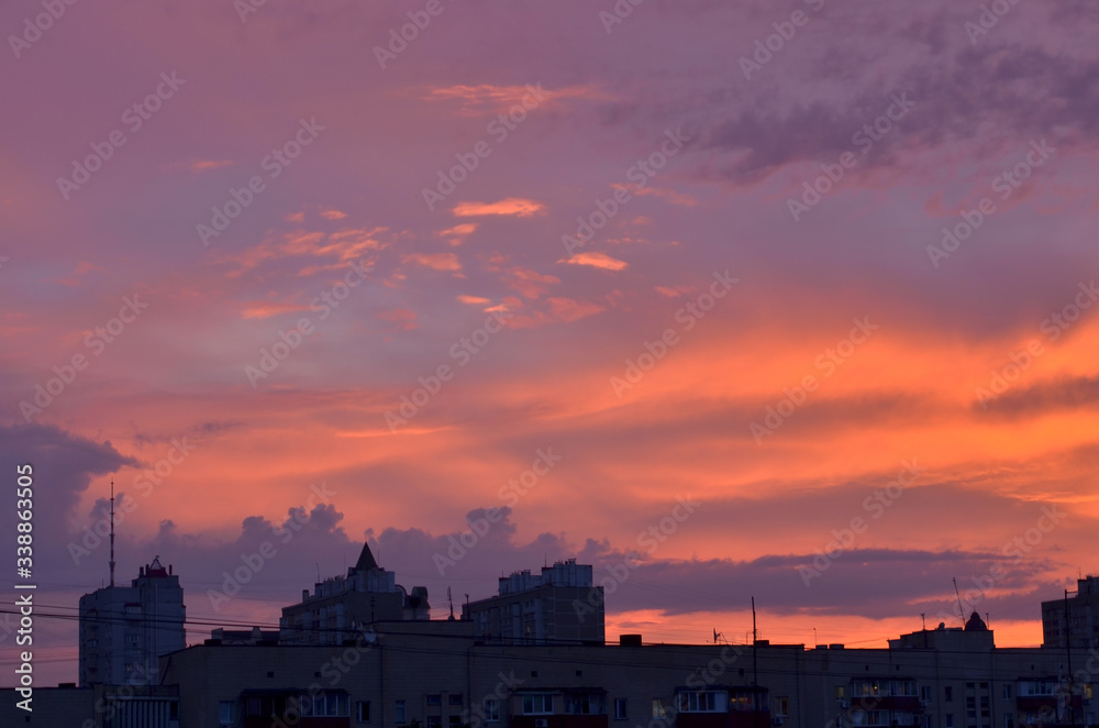 Buildings in city at sunset. City illuminated by the last rays of the setting sun. Magical purple sunset. Minimalism. Place for your text