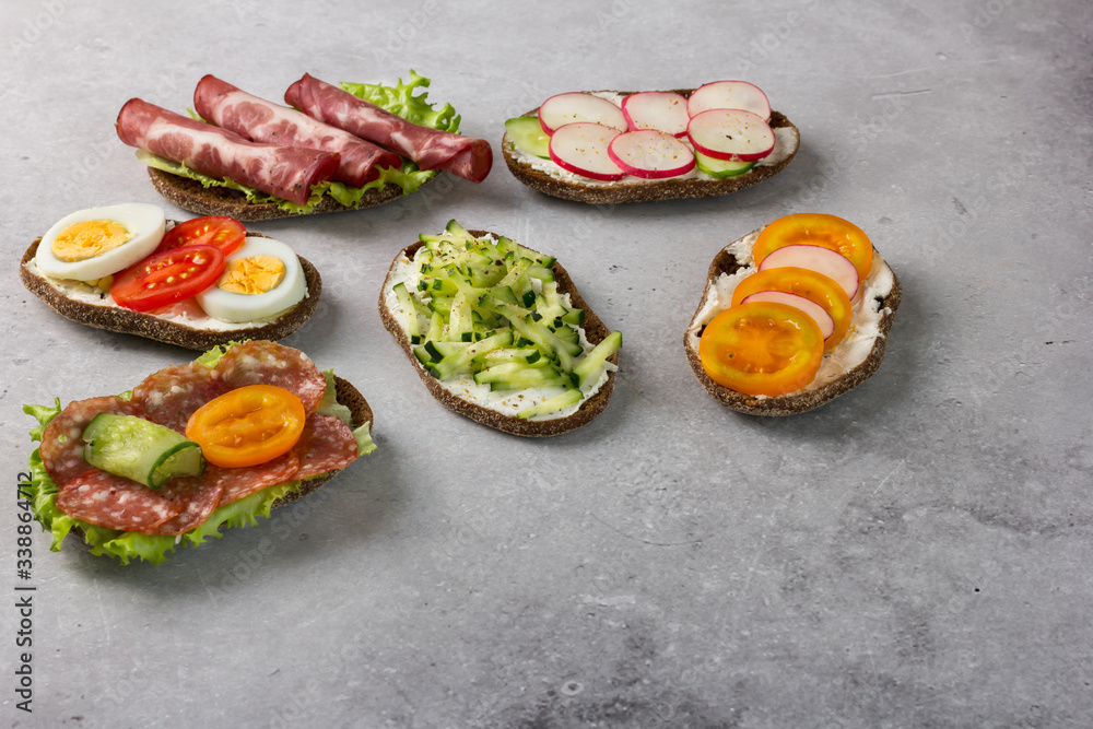 Open sandwiches on rye bread with cream cheese, ham, egg, radish, tomato, cucumber.