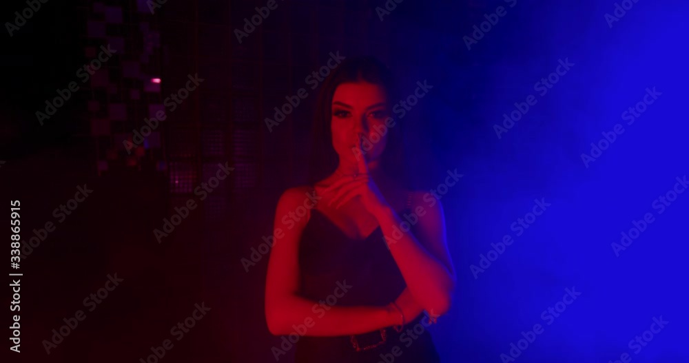 A beautiful girl is sexually leanning a finger to her lips. Fashion looks. Shooting in blue and red neon. 4k A beautiful girl is sexually leanning a finger to her lips. Fashion looks. Shooting in blue and red neon. 4k