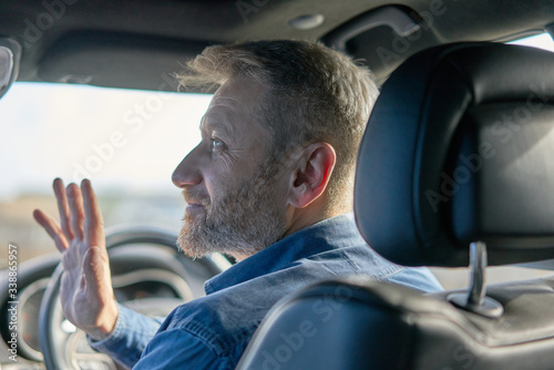 Foto Profile of a friendly car driver with graying hair and beard taken from inside t