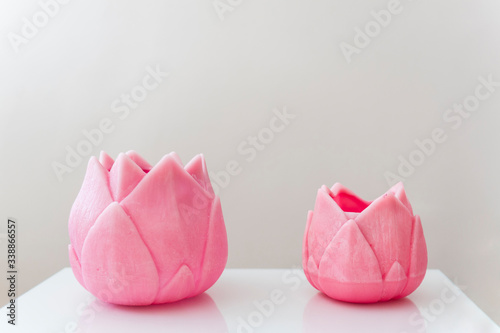 Two pink flower shaped candles with white background. Zen and minimalist background with pastel tones. Space for text
