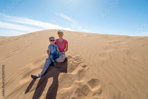 Mother and her 2 years old son enjoying sitting on Sahara sand dunes, Africa © malajscy