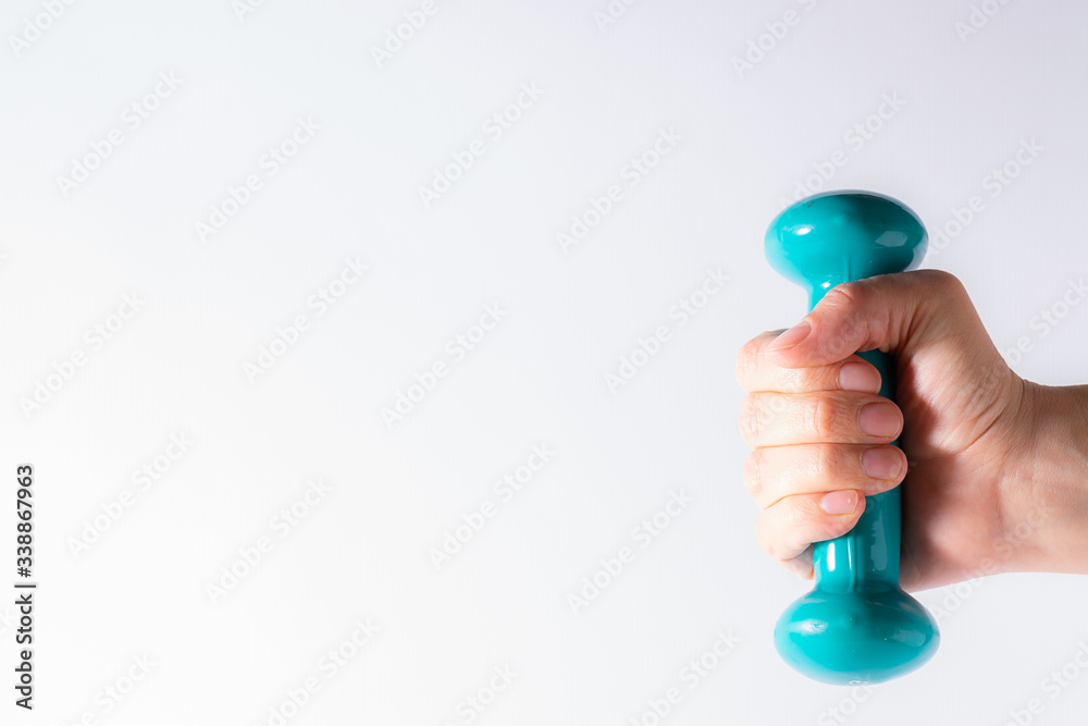 Female’s hand holding dumbbell on white background with copy space for your design. Healthy lifestyle and home training concept. Female’s hand holding dumbbell on white background with copy space for your design. Healthy lifestyle and home training concept.
