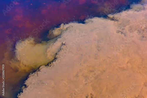Caustic toxic emissions brown, purple into the pond, bright contrasting spots on the water. The spread of poison in the ecosystem. The concept of pollution of life threatening, ecology. © aapsky