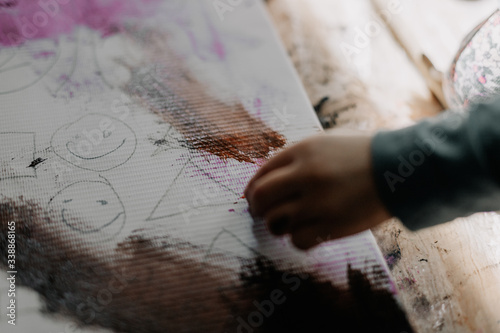 25.06.2018 Vinnitsa, Ukrane: little girl draws oil paints on canvas with bone and palette knife sitting on floor near window