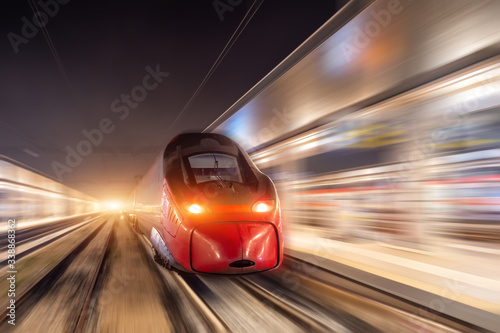 Night passenger high-speed train passing the station in the city.
