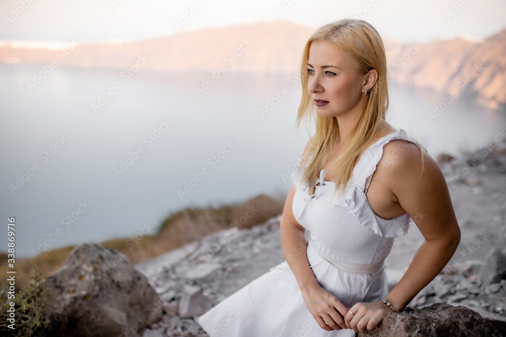 Girl in a white dress on a background of mountains and sea