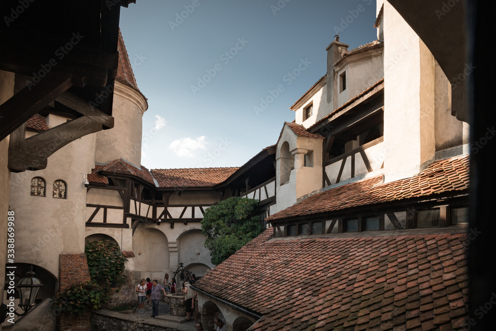 BRAN, ROMANIA - AUGUST 2019: Bran Castle best known as Dracula's Castle, home of Vlad Tepes Dracula, inner yard and balcony with walking people in sunlight, Brasov, Transylvania, Romania