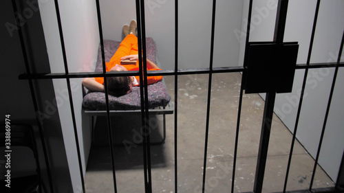 The criminal sleeps on the bed behind the bars