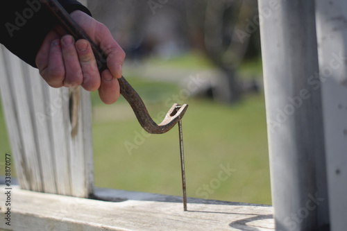 Worker pulls a nail from a wood with a crowbar. Rusty scrap with old nail close up. Hand tool © A.Hetmanenko