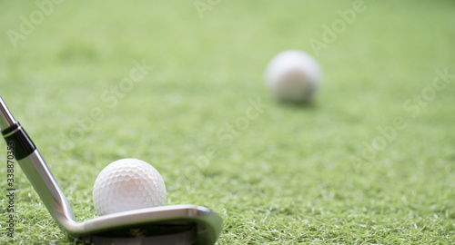 Selective golf club and golf ball on green grass background.Iron golf club hitting ball into a hole.Outdoor sport.