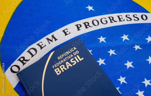 Brazilian Passport on top of Brazilian Flag. Brazilian Flag Motto: “Ordem e Progresso” (Order and Progress). Travel concept. photo