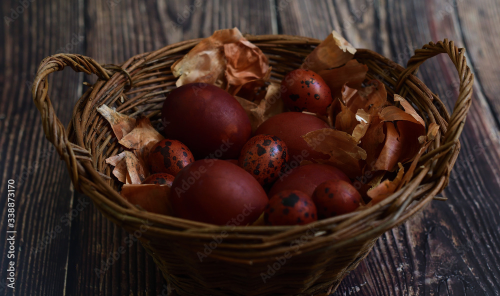 Naturally Eggs painted with onion peel and quail feathers in a wicker basket.Eco paint. Happy Easter card. Flat lay. old eco-friendly method. Copy space for greeting text Naturally Eggs painted with onion peel and quail feathers in a wicker basket.Eco paint. Happy Easter card. Flat lay. old eco-friendly method. Copy space for greeting text