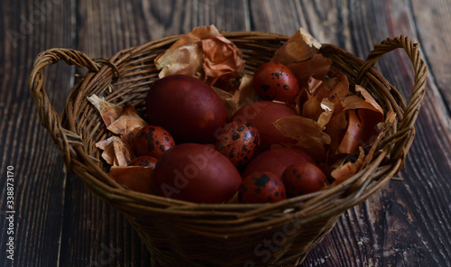 Naturally Eggs painted with onion peel and quail feathers in a wicker basket.Eco paint. Happy Easter card. Flat lay. old eco-friendly method. Copy space for greeting text