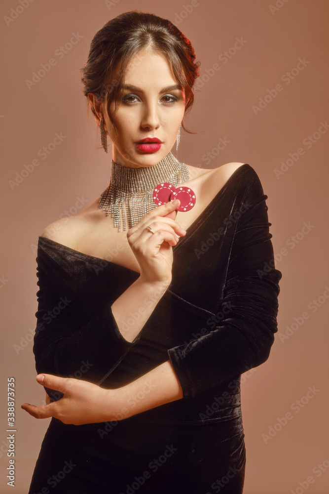 Brunette model in black dress and shiny jewelry. She is showing two red ...