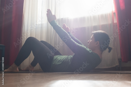 Young caucasian woman practicing yoga asana Ardha Navasana boat pose exercise at the living room. Stay at home and do yoga concept