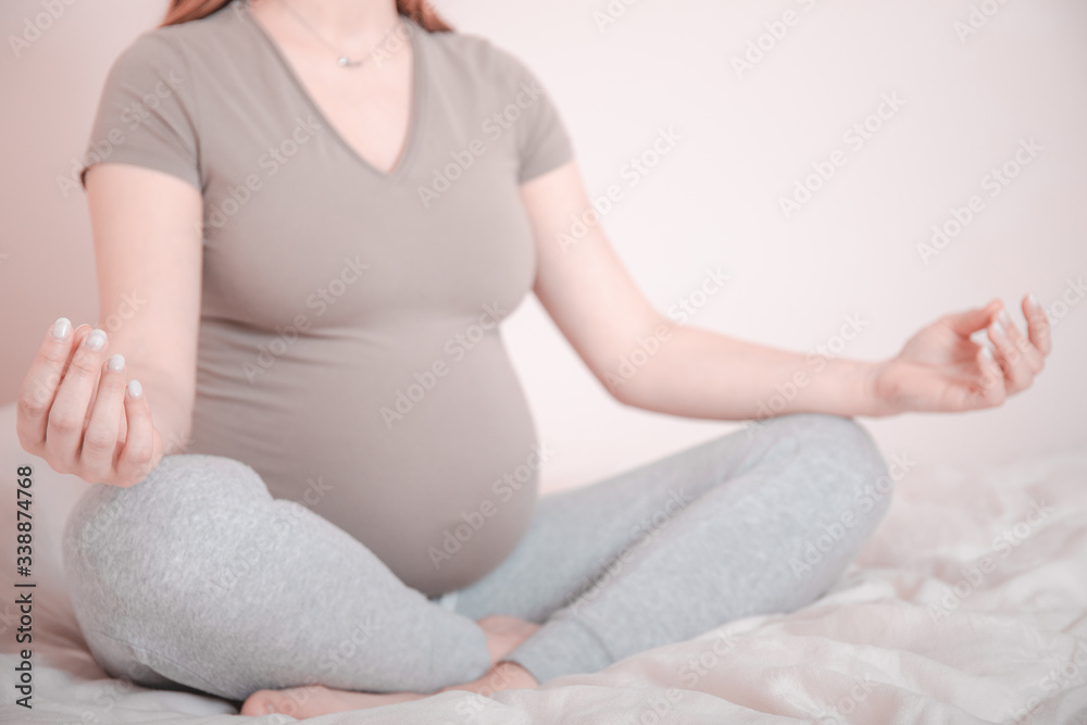 Meditating on maternity. Close-up of pregnant woman meditating while sitting in lotus position. Pregnant yoga woman relaxing and meditating. Meditating on maternity. Close-up of pregnant woman meditating while sitting in lotus position. Pregnant yoga woman relaxing and meditating.