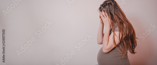 Sad woman crying while sitting on bed in her bedroom. Stressed pregnant woman or mother problems.