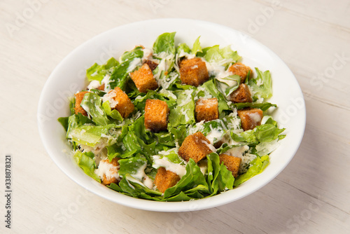 Vászonkép Traditional caesar salad in a white bowl on a white table.