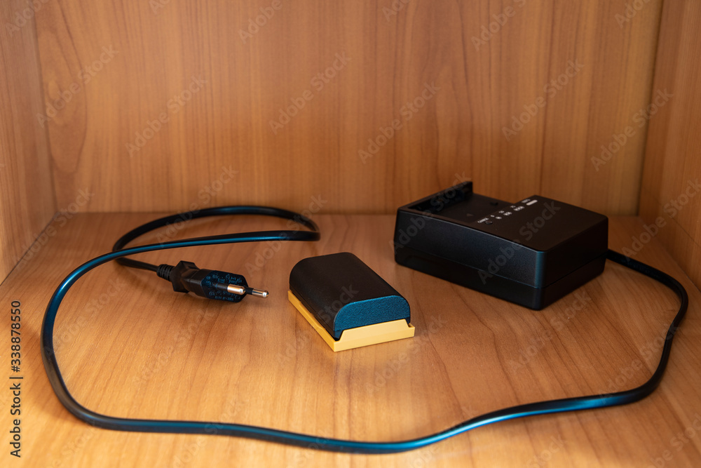 camera charger and battery accessory equipment object in wooden cupboard cell surface camera charger and battery accessory equipment object in wooden cupboard cell surface