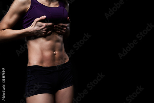 Fitness woman in training.Strong abs showing on a dark background.