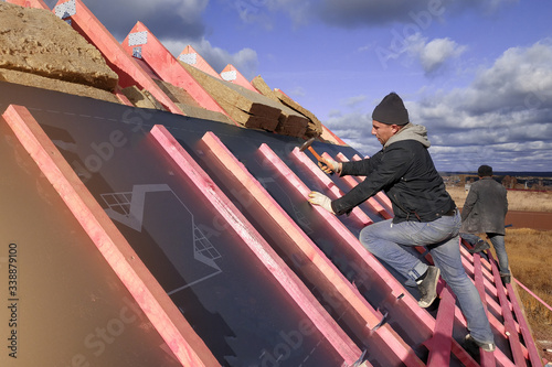 Insulation and waterproofing of the roof surface, the worker nails the film to the boards.