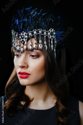 Portrait of gorgeous brunette woman in luxurious headdress posing against dark studio background. Beautiful girl with a healthy clean skin and with red lips.
