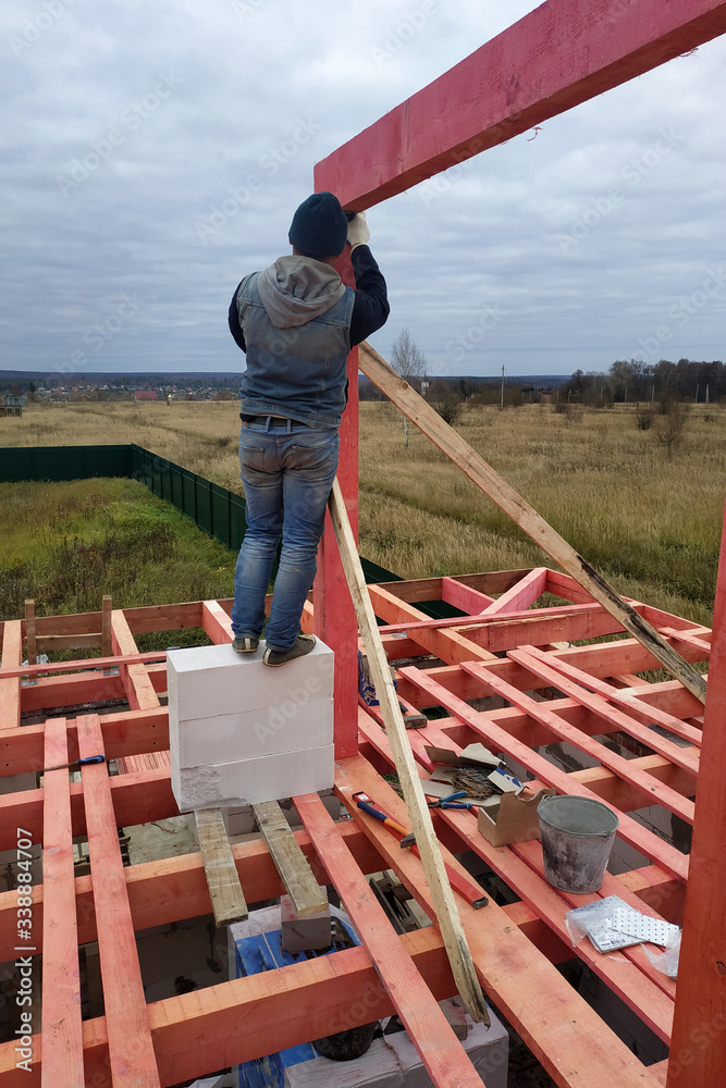 Joiner on roof installation, hammer hammering nail into wooden beam. Joiner on roof installation, hammer hammering nail into wooden beam.