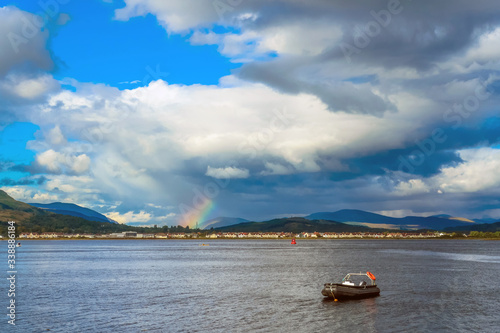 Fort William, Highland, Scotland / UK - August 2014: An inflatable boat anchored in the middle of Loch Eil with the rainbow and Fort William in the distance