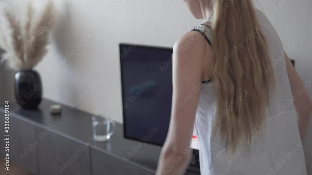 girl in sportswear repeats fitness exercises for the instructor on the TV screen. exercise at home to maintain body shape girl in sportswear repeats fitness exercises for the instructor on the TV screen. exercise at home to maintain body shape