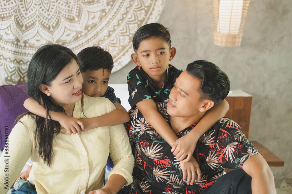 Obraz premium Southeast Asian family spending time at home. Happy Indonesian or malasian parents and children laying in bed having fun together