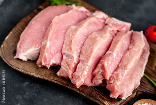 raw pork steaks with spices on a cutting board on a stone background