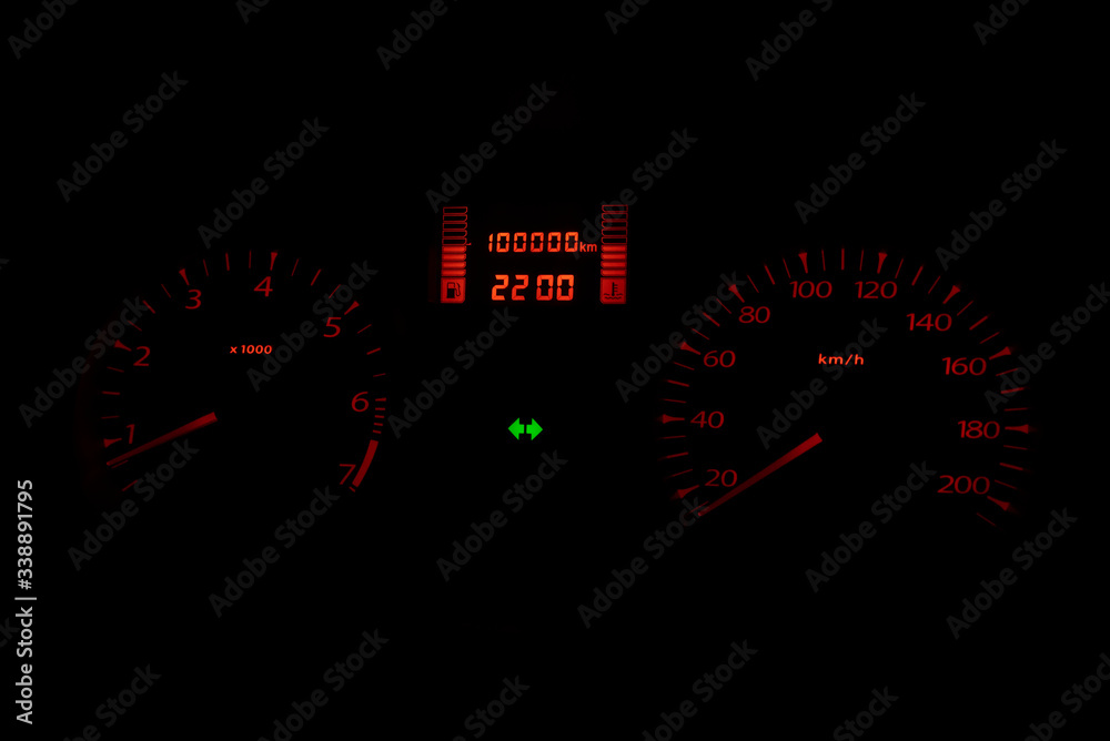 Black automobile dashboard with orange lights of odometer and green emergency lights Selective focus Black automobile dashboard with orange lights of odometer and green emergency lights Selective focus