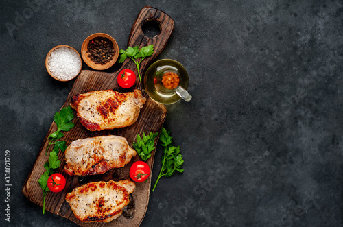 grilled pork steaks with spices on a cutting board on a stone background with copy space for your text