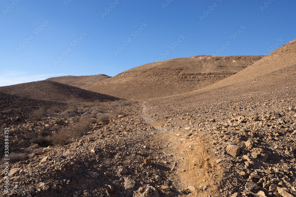 The small path among sandstone hills with rocky slopes and the clean blue sky