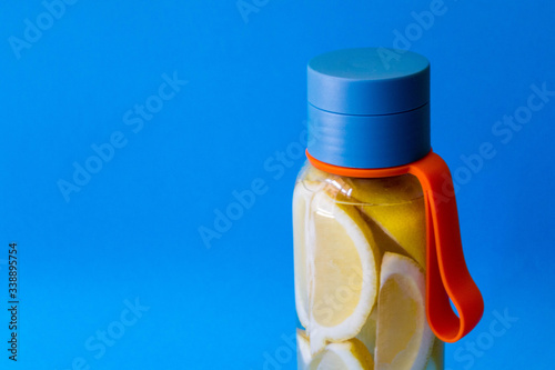 flat lay style concept of healthy lifestyle, sport and fitness at home. Bottle of water with lemons on blue background photo