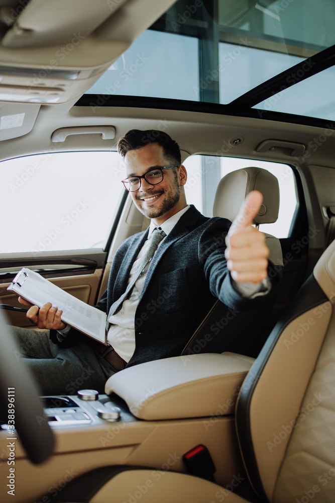 Car seller working in showroom and quality control checking of car details for the last time before buyer comes. Car seller working in showroom and quality control checking of car details for the last time before buyer comes.